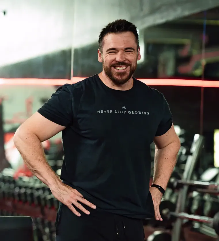 Dan Fitzsimons, personal trainer in Wellingborough, smiling with his hands on his hips in the gym